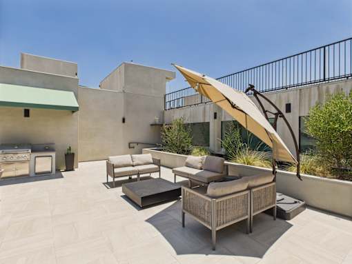 A patio with a couch, table, and umbrella.