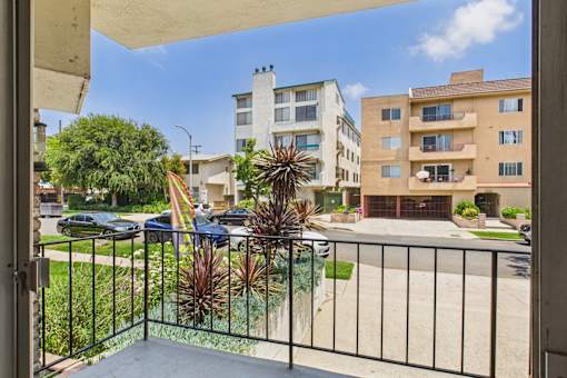 A balcony view of a residential area with buildings and cars.