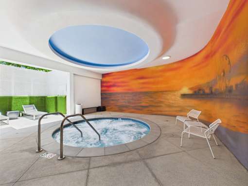 A hot tub in a room with a mural of a sunset.
