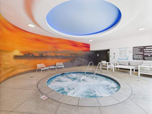 A hot tub in a room with a sunset mural on the wall.