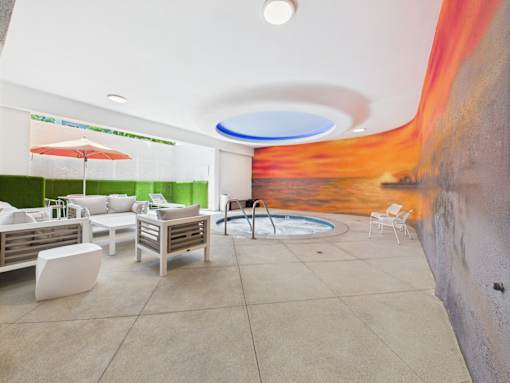 A modern outdoor seating area with a pool and a mural on the wall.