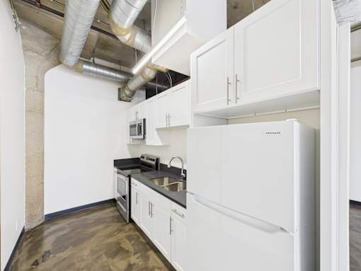 A kitchen with white cabinets and a white fridge.