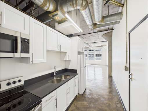 A kitchen with white cabinets and a black countertop.
