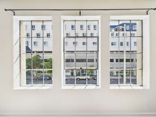 Three windows with white frames and a view of a street with cars and buildings.
