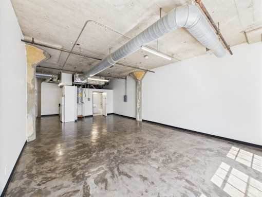 A large empty room with a concrete floor and white walls.