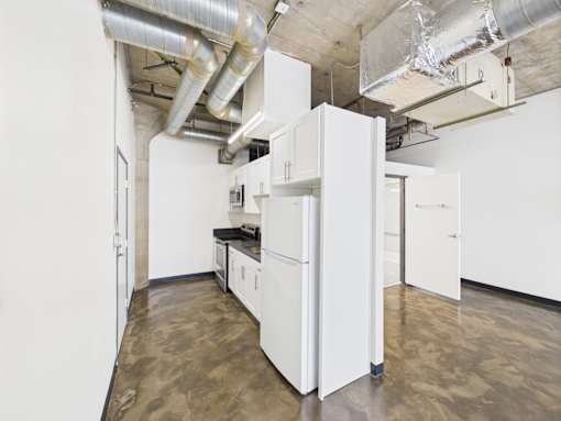 A kitchen with white cabinets and a concrete floor.