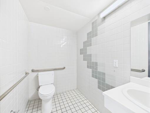 A white toilet sits in a bathroom with a white tub and a white sink.