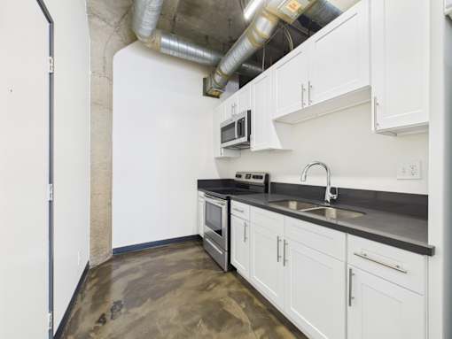 A kitchen with white cabinets and a black countertop.