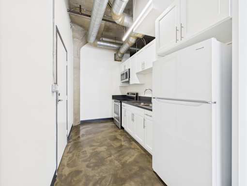 A kitchen with white cabinets and a white refrigerator.