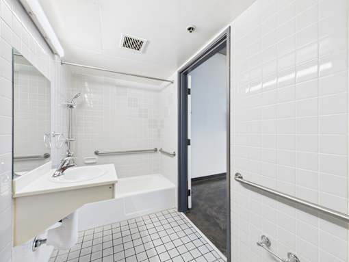 A white bathroom with a sink, mirror, and shower.