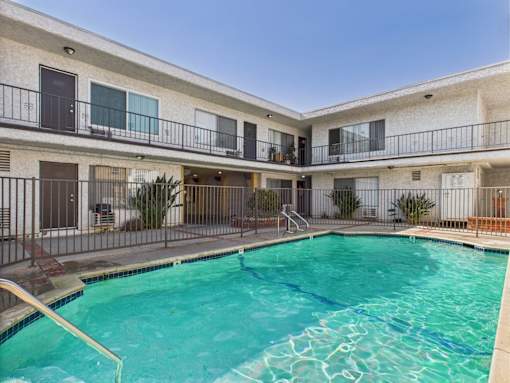 A swimming pool in front of a building with balconies.