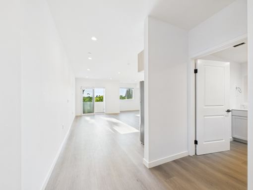 A long white hallway with a door on the right.