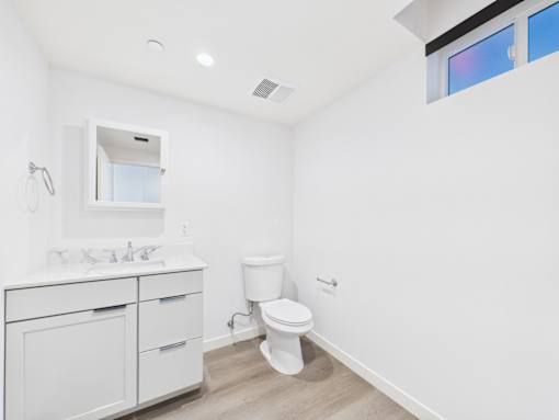 A white bathroom with a toilet, sink, and mirror.