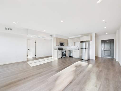 A spacious kitchen with white appliances and a wooden floor.
