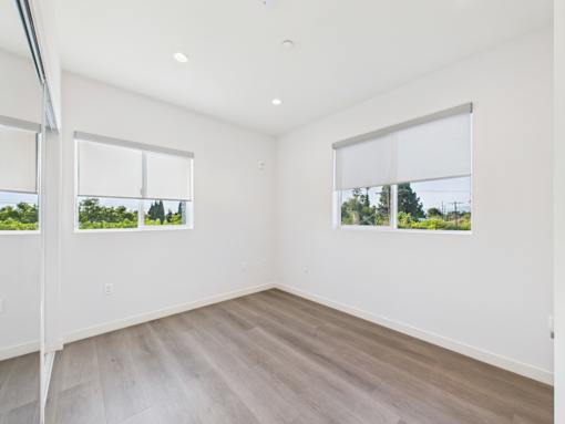 A room with a white wall and a window with a view of trees.