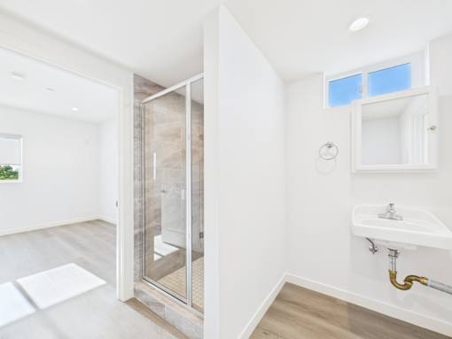 A bathroom with a sink, mirror, and shower.