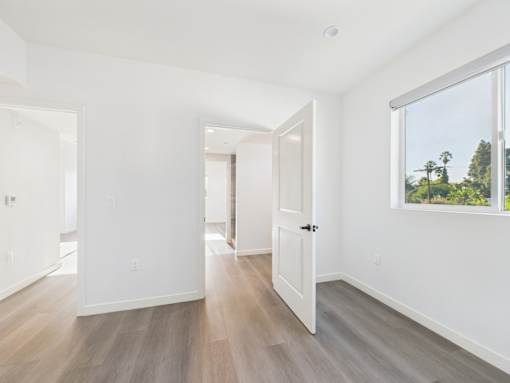 A room with white walls and wooden flooring with a door on the right.