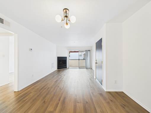 A long hallway with wood floors and a chandelier.