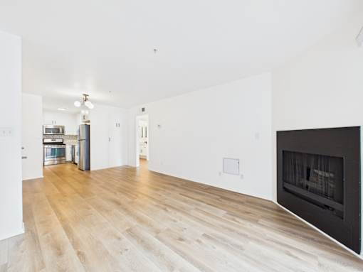 A large, empty room with a fireplace and wooden flooring.