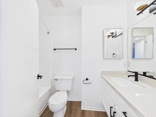 A white bathroom with a toilet, sink, and mirror.