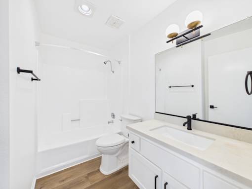 A white bathroom with a toilet, sink, and mirror.