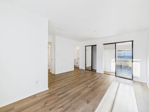 A spacious room with wooden flooring and white walls.