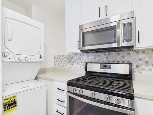 A kitchen with a white oven, microwave, and stove top.