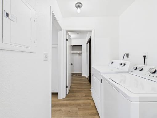A white kitchen with wooden floors and white appliances.