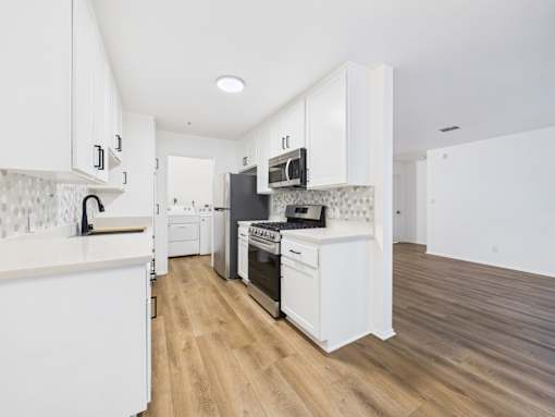 A kitchen with white cabinets and a wooden floor.