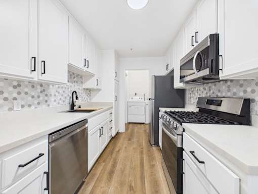 A kitchen with white cabinets and a wooden floor.