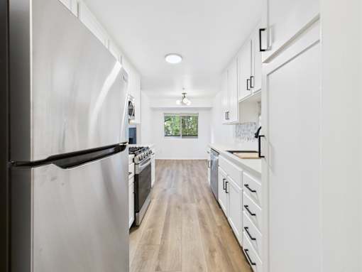 A modern kitchen with a refrigerator on the left and a stove top oven in the middle.