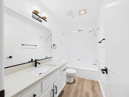 A white bathroom with a toilet, sink, and mirror.
