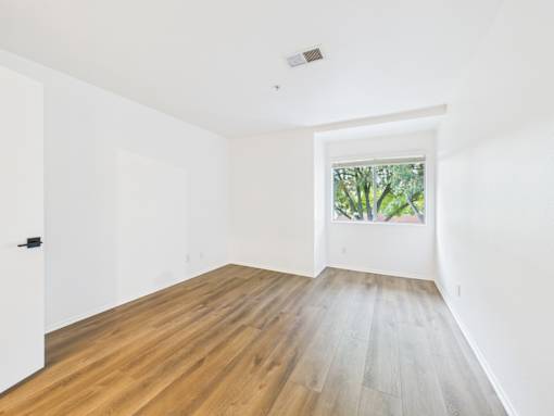 A room with a window and a wooden floor.