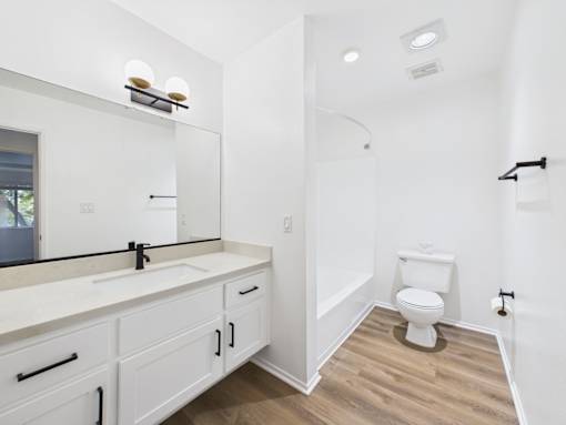A white bathroom with a toilet, sink, and mirror.