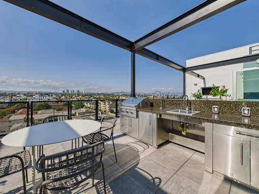 A patio with a table and chairs overlooking a city skyline.