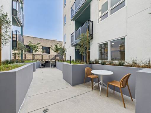 A patio with a table and chairs is surrounded by buildings.
