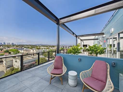 Two chairs are on a balcony with a view of the city.