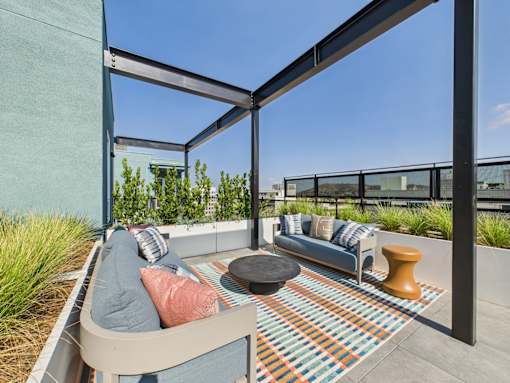 A patio with a couch, pillows, and a table.