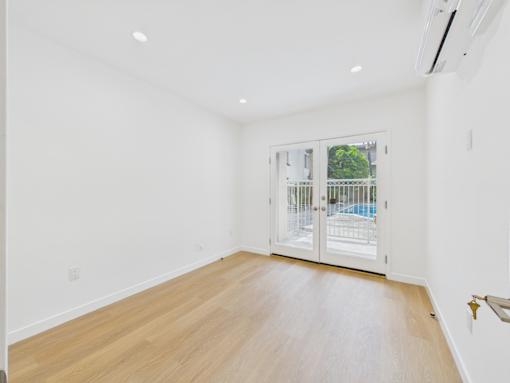 A room with a wooden floor and a sliding glass door leading to a balcony.