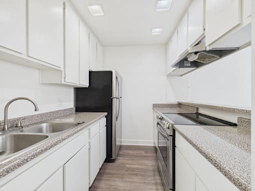 A kitchen with white cabinets and a black refrigerator.