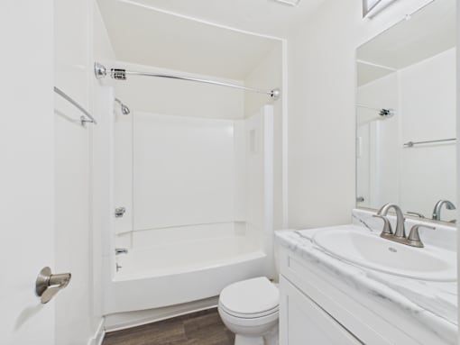 A white bathroom with a toilet, sink, and bathtub.