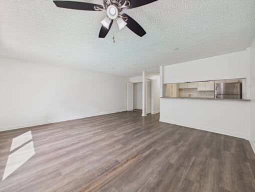 A room with a ceiling fan and wooden flooring.