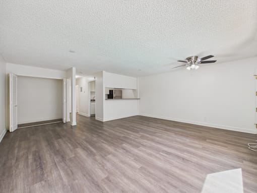 A room with a ceiling fan and light fixture, and a wooden floor.