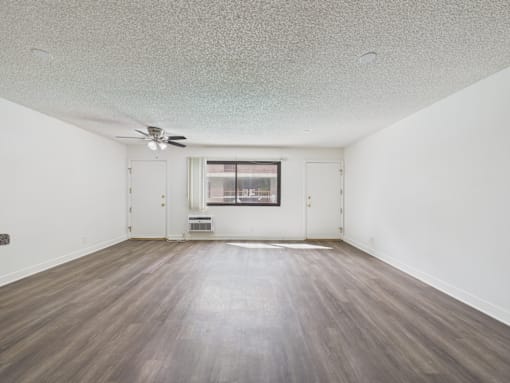A room with a ceiling fan and a window with blinds.