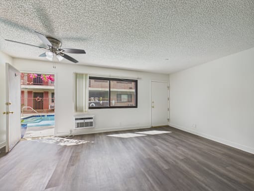 A room with a ceiling fan and a window overlooking a pool.