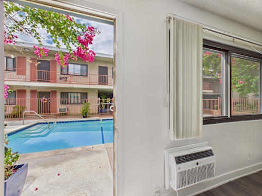 A white wall with a window and air conditioner unit.