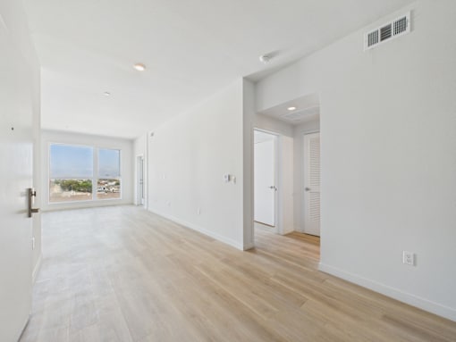 A long, empty hallway with a door on the left and a window on the right.