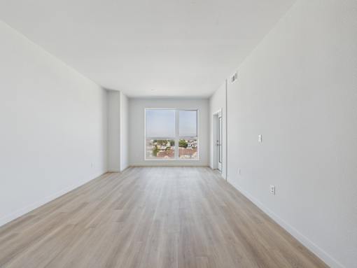 A long, empty room with wooden floors and white walls.