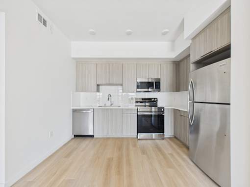 A modern kitchen with wooden floors and stainless steel appliances.
