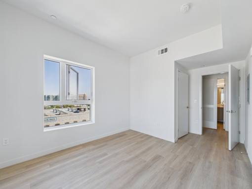 A white room with a picture of a cityscape on the wall and a wooden floor.